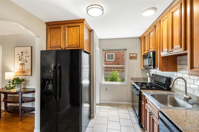 346 Madison Ave, Saint Louis, MO 63119 - kitchen with black appliances, backsplash, brown cabinetry, light countertops, and arched walkways