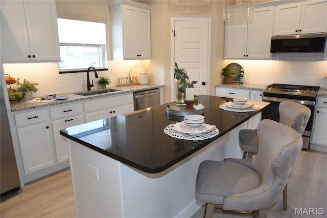 8748 Wendell Creek Dr, Saint Jacob, IL 62281 - kitchen with stainless steel appliances, white cabinets, a breakfast bar area, tasteful backsplash, and light wood-style flooring