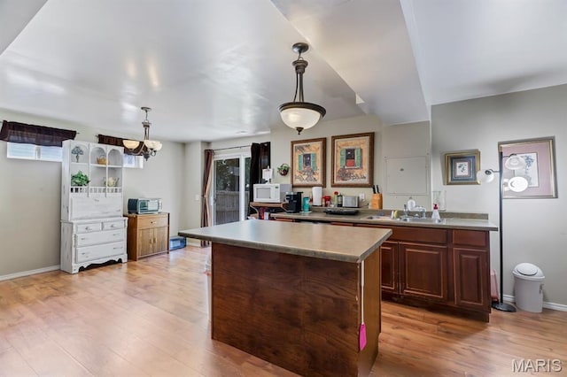 25 Saint Kathleen Ct, Troy, MO 63379 - kitchen featuring white microwave, a kitchen island, light wood-style flooring, and decorative light fixtures