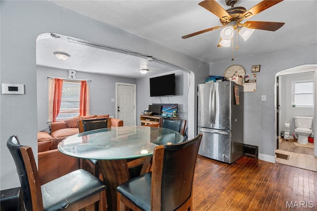 5211 Fletcher St, Jennings, MO 63136 - dining space featuring dark wood finished floors, arched walkways, ceiling fan, and healthy amount of natural light