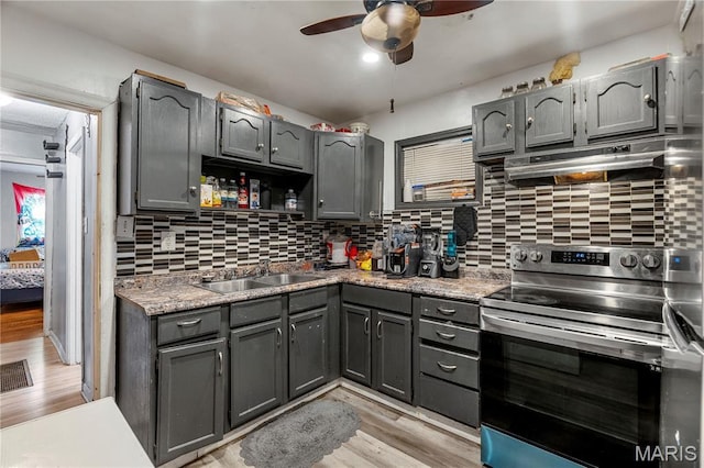 5211 Fletcher St, Jennings, MO 63136 - kitchen with stainless steel electric range, under cabinet range hood, light wood-type flooring, a ceiling fan, and gray cabinetry