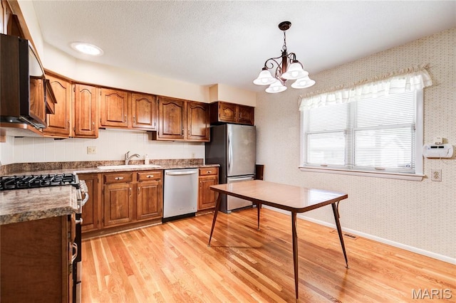 4828 Plum Tree Ln, Hazelwood, MO 63042 - kitchen featuring appliances with stainless steel finishes, light wood-type flooring, wallpapered walls, a chandelier, and hanging light fixtures