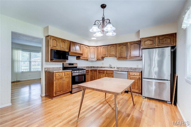 4828 Plum Tree Ln, Hazelwood, MO 63042 - kitchen with stainless steel appliances, wallpapered walls, premium range hood, a chandelier, and light wood-style flooring