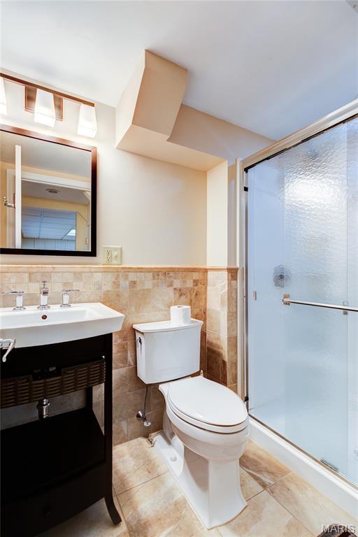 4828 Plum Tree Ln, Hazelwood, MO 63042 - bathroom featuring tile patterned floors, a shower stall, vanity, tile walls, and a wainscoted wall
