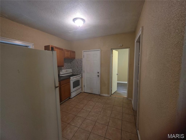 3421 Belt Ave, Saint Louis, MO 63120 - kitchen featuring white appliances, a textured wall, light tile patterned floors, a textured ceiling, and dark countertops