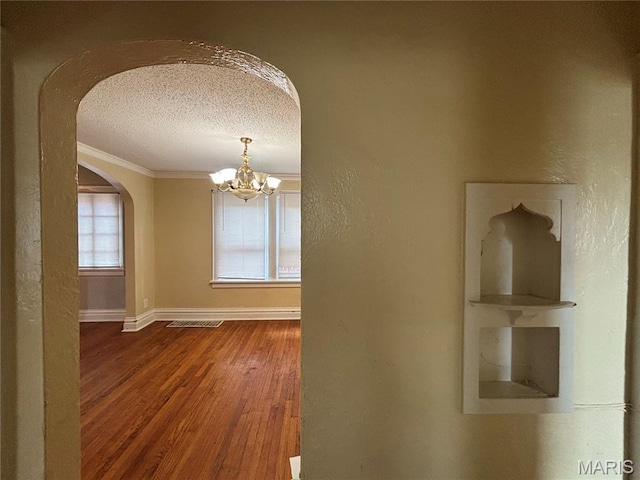 6104 N Pointe Blvd, Saint Louis, MO 63147 - corridor featuring arched walkways, a textured ceiling, a chandelier, wood finished floors, and ornamental molding