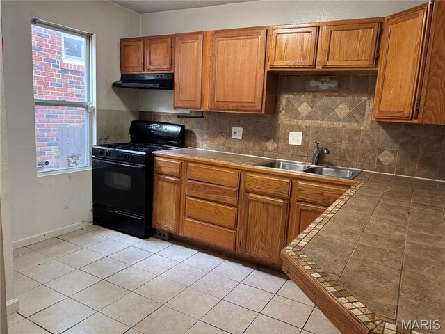 6104 N Pointe Blvd, Saint Louis, MO 63147 - kitchen featuring gas stove, under cabinet range hood, brown cabinets, and tile counters