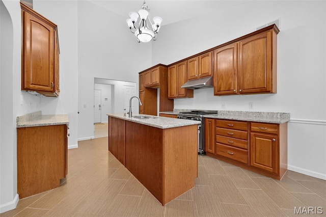 36 Mountain Laurel Dr, Saint Peters, MO 63376 - kitchen with stainless steel range with gas stovetop, under cabinet range hood, a high ceiling, brown cabinetry, and a chandelier