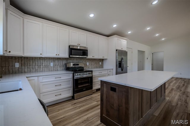 1817 Vadie Ave, Lebanon, MO 65536 - kitchen featuring stainless steel appliances, decorative backsplash, light wood finished floors, white cabinets, and recessed lighting