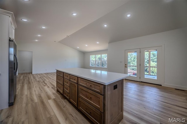 1817 Vadie Ave, Lebanon, MO 65536 - kitchen with stainless steel fridge, vaulted ceiling, light wood-style flooring, a center island, and light countertops