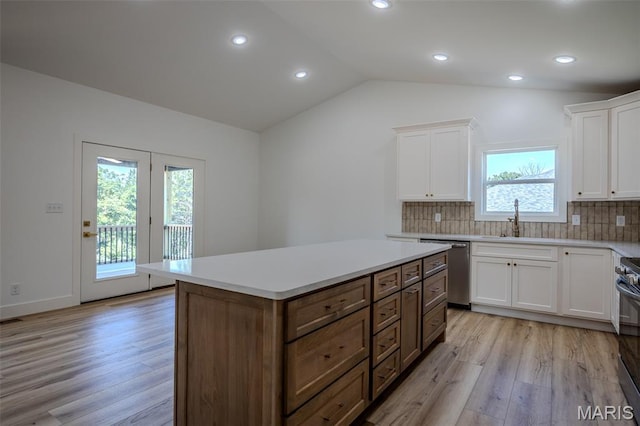 1817 Vadie Ave, Lebanon, MO 65536 - kitchen featuring appliances with stainless steel finishes, light wood-type flooring, white cabinetry, lofted ceiling, and decorative backsplash