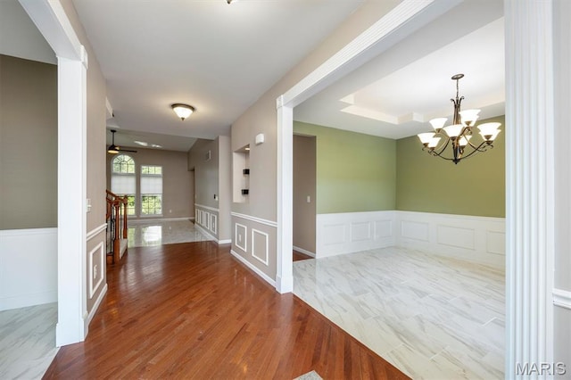 1305 Monarch Lake Ln, Shiloh, IL 62221 - empty room featuring ornate columns, a decorative wall, wood finished floors, a chandelier, and wainscoting