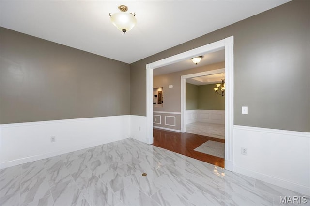1305 Monarch Lake Ln, Shiloh, IL 62221 - spare room featuring a chandelier, a wainscoted wall, and marble look tiles