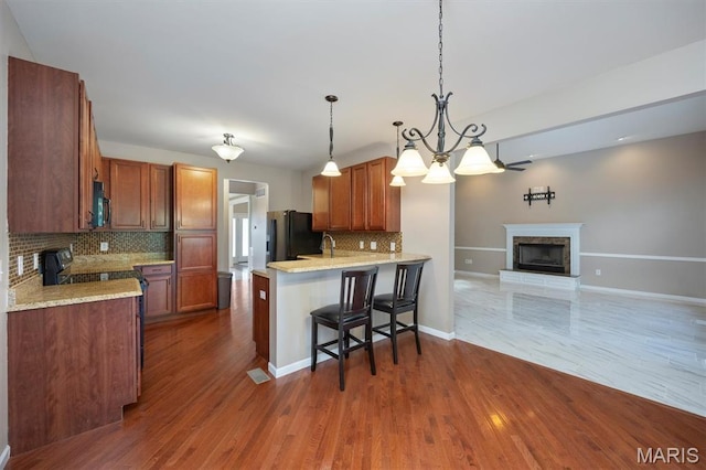 1305 Monarch Lake Ln, Shiloh, IL 62221 - kitchen featuring black microwave, stove, a fireplace with raised hearth, backsplash, and freestanding refrigerator
