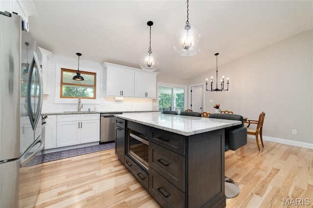 8870 State Road Nn, Cedar Hill, MO 63016 - kitchen with stainless steel appliances, light wood-style floors, white cabinetry, vaulted ceiling, and backsplash