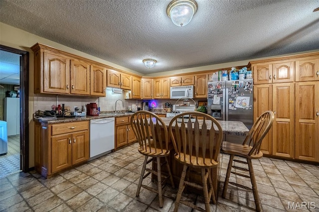 30053 Emily Ln, Lebanon, MO 65536 - kitchen with white appliances, stone tile flooring, brown cabinets, and a textured ceiling
