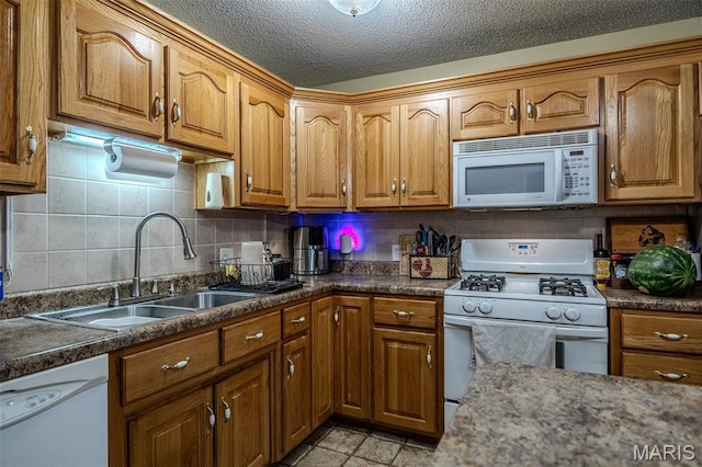 30053 Emily Ln, Lebanon, MO 65536 - kitchen with white appliances, brown cabinets, tasteful backsplash, dark countertops, and a textured ceiling
