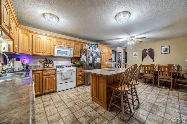 30053 Emily Ln, Lebanon, MO 65536 - kitchen featuring white appliances, stone tile flooring, a breakfast bar, a ceiling fan, and a textured ceiling