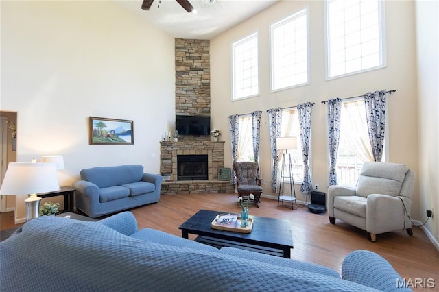 11907 Pine Forest Dr, Rolla, MO 65401 - living area with a towering ceiling, a ceiling fan, wood finished floors, and a stone fireplace