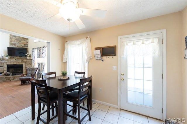 11907 Pine Forest Dr, Rolla, MO 65401 - dining area featuring light tile patterned floors, plenty of natural light, a fireplace, a ceiling fan, and a textured ceiling