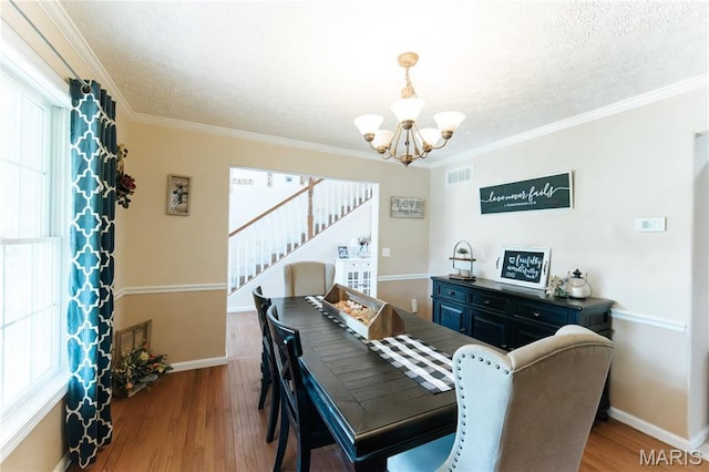 11907 Pine Forest Dr, Rolla, MO 65401 - dining room with a chandelier, stairs, wood finished floors, a textured ceiling, and ornamental molding