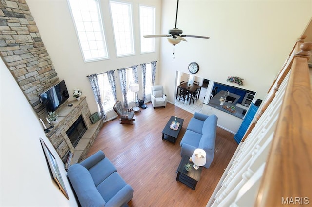11907 Pine Forest Dr, Rolla, MO 65401 - living room with a stone fireplace, a high ceiling, healthy amount of natural light, a ceiling fan, and wood finished floors