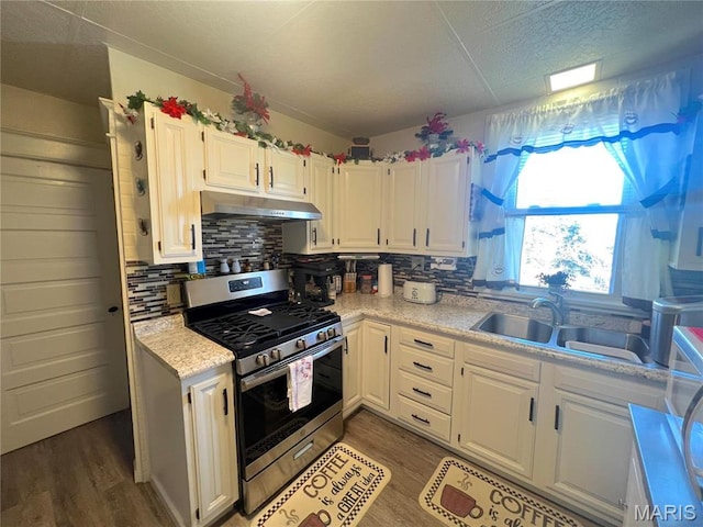 606 Olive St, Hannibal, MO 63401 - kitchen with stainless steel gas range, under cabinet range hood, light countertops, and white cabinetry