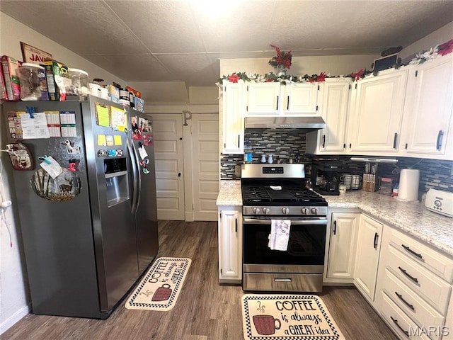 606 Olive St, Hannibal, MO 63401 - kitchen featuring appliances with stainless steel finishes, dark wood-style floors, decorative backsplash, under cabinet range hood, and white cabinetry