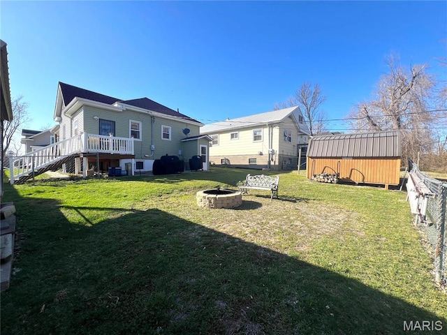 606 Olive St, Hannibal, MO 63401 - rear view of house with a fire pit, a lawn, stairs, a wooden deck, and a storage unit
