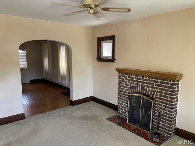 5461 Eichelberger St, Saint Louis, MO 63109 - unfurnished living room featuring carpet, arched walkways, a ceiling fan, and a fireplace
