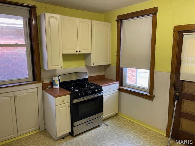 5461 Eichelberger St, Saint Louis, MO 63109 - kitchen featuring stainless steel range with gas cooktop, white cabinetry, dark countertops, and light floors