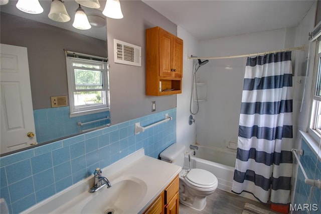 1513 Colonial Dr, Godfrey, IL 62035 - bathroom featuring tile walls, vanity, shower / bathtub combination with curtain, a wainscoted wall, and wood finished floors