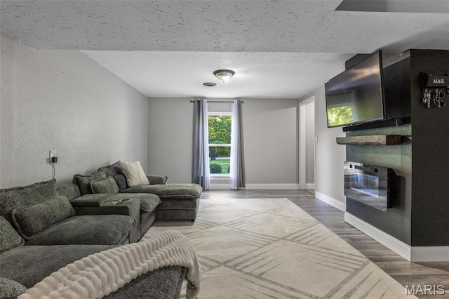 112 Dale Dr, Hillsboro, MO 63050 - living area featuring a textured ceiling, wood finished floors, a textured wall, and a glass covered fireplace