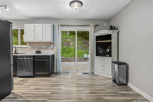 112 Dale Dr, Hillsboro, MO 63050 - kitchen featuring appliances with stainless steel finishes, light countertops, white cabinets, light wood-style flooring, and a textured ceiling