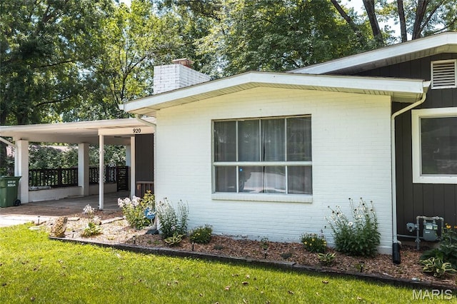 920 E 7th St, Rolla, MO 65401 - view of side of home featuring a chimney, a carport, brick siding, and a yard