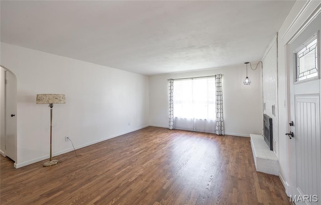 920 E 7th St, Rolla, MO 65401 - unfurnished living room featuring healthy amount of natural light, wood finished floors, heating unit, and arched walkways
