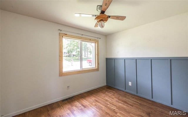 920 E 7th St, Rolla, MO 65401 - empty room with wood finished floors, a ceiling fan, a decorative wall, and wainscoting