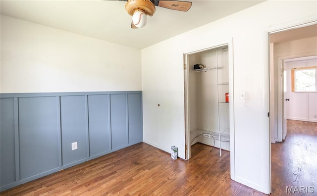 920 E 7th St, Rolla, MO 65401 - unfurnished bedroom featuring wood finished floors, a decorative wall, wainscoting, and ceiling fan