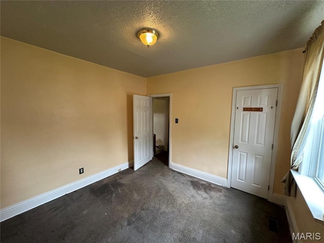 720 Tiffin Ave, Ferguson, MO 63135 - unfurnished bedroom featuring dark carpet and a textured ceiling