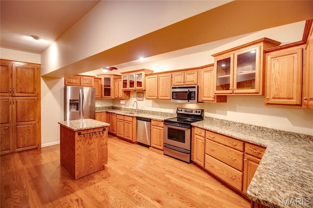 417 Prospect St Unit A, Alton, IL 62002 - kitchen featuring stainless steel appliances, a center island, light wood finished floors, light stone counters, and glass insert cabinets