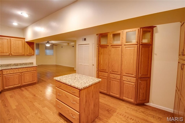417 Prospect St Unit A, Alton, IL 62002 - kitchen with light wood finished floors, glass insert cabinets, a center island, and light stone countertops