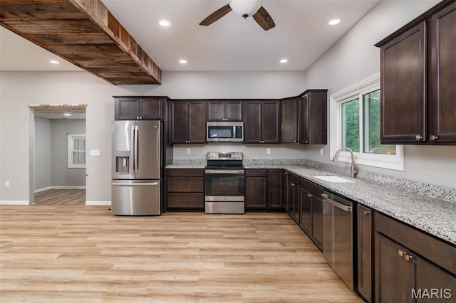 18347 Windy Hill Rd, Staunton, IL 62088 - kitchen featuring stainless steel appliances, light wood-style flooring, ceiling fan, dark brown cabinetry, and light stone counters