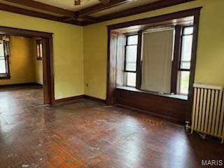 570 Washington Pl E, St Louis, IL 62205 - empty room featuring radiator, plenty of natural light, beam ceiling, and coffered ceiling