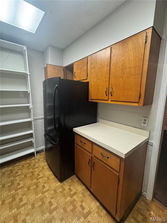 2544 State St, Granite City, IL 62040 - kitchen with freestanding refrigerator, light floors, light countertops, and brown cabinetry