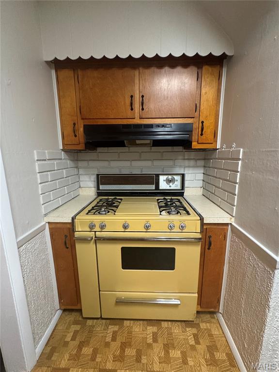2544 State St, Granite City, IL 62040 - kitchen featuring white range with gas stovetop, exhaust hood, light countertops, and brown cabinets