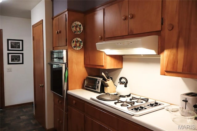 337 S Elm St, Dexter, MO 63841 - kitchen featuring under cabinet range hood, stainless steel oven, white gas cooktop, light countertops, and brown cabinetry