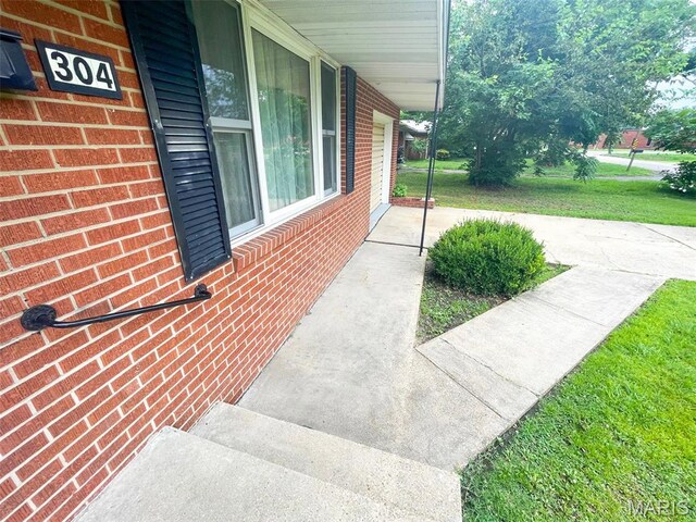 304 W Oak St, Dexter, MO 63841 - view of home's exterior with brick siding, a yard, and a porch