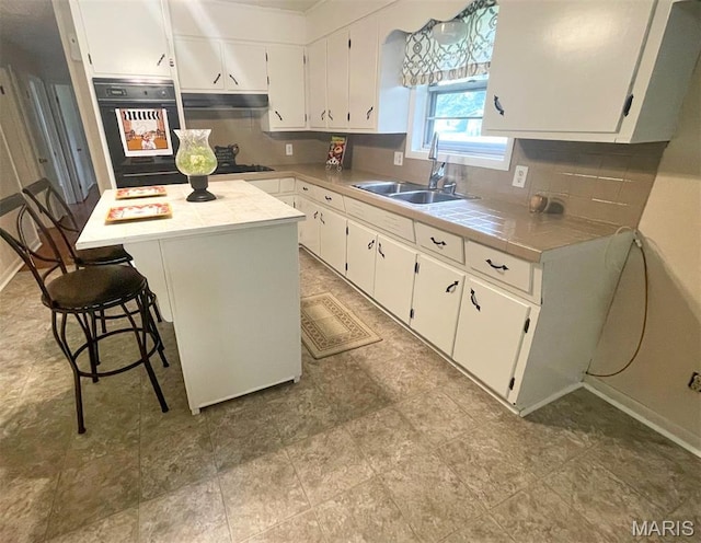 304 W Oak St, Dexter, MO 63841 - kitchen featuring black oven, decorative backsplash, white cabinets, and under cabinet range hood