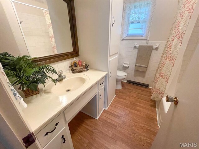 304 W Oak St, Dexter, MO 63841 - bathroom featuring tile walls, vanity, wood finished floors, a wainscoted wall, and shower / bath combination with curtain