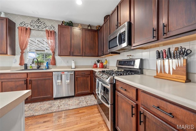 7742 Ardmore Dr, Ofallon, MO 63368 - kitchen featuring stainless steel appliances, light wood-style flooring, light countertops, and backsplash